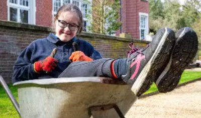 Student van Parc Spelderholt werkt buiten met een kruiwagen Student van Parc Spelderholt werkt buiten met een kruiwagen